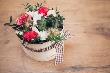 Şapka kutusunda güzel bir çiçek aranjmanı, ahşap arka plan. 