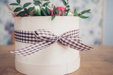 Şapka kutusunda güzel bir çiçek aranjmanı, ahşap arka plan. 