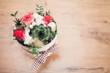Şapka kutusunda güzel bir çiçek aranjmanı, ahşap arka plan. 