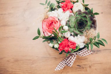 Şapka kutusunda güzel bir çiçek aranjmanı, ahşap arka plan. 