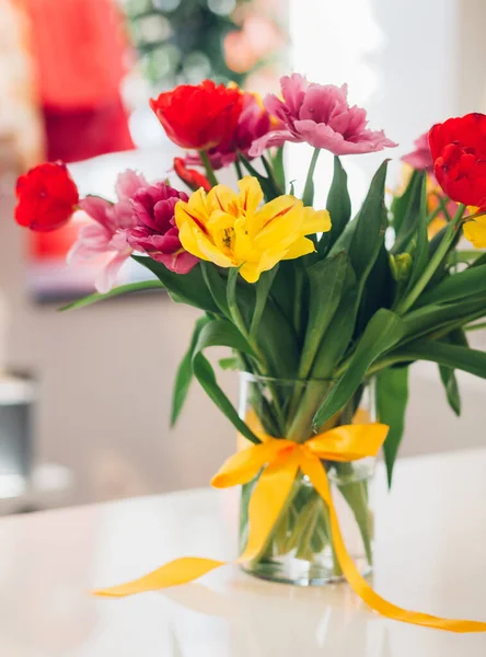 花瓶上的结蝴蝶结 水里的花 不同颜色的郁金香 家居装饰 — 图库照片