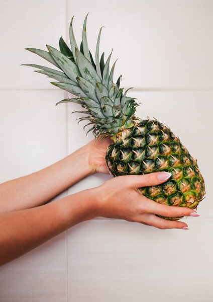 Female hands holding ripe pineapple on a white background