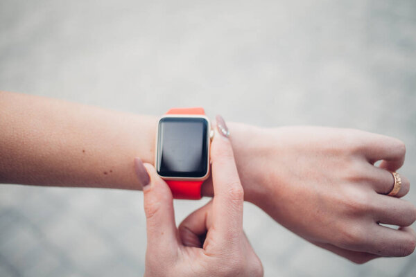 Фото женских рук, касающихся экрана, общий дизайн умных часов. Киноэффекты, размытый фон
