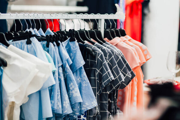 Rack with collection of clothes in dressing room, female dresses closeup 