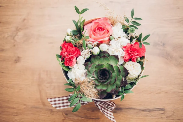 Şapka kutusunda güzel bir çiçek aranjmanı, ahşap arka plan. 