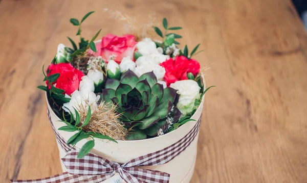 Şapka kutusunda güzel bir çiçek aranjmanı, ahşap arka plan. 