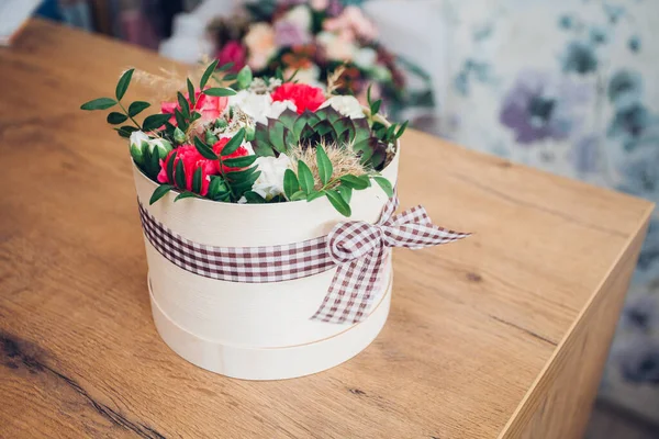 Şapka kutusunda güzel bir çiçek aranjmanı, ahşap arka plan. 