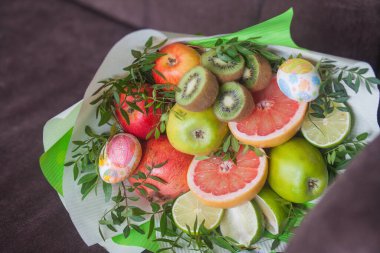 Çiçek buketi ve kalın kağıda sarılmış taze narenciye meyveleri.