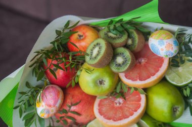 Çiçek buketi ve kalın kağıda sarılmış taze narenciye meyveleri.