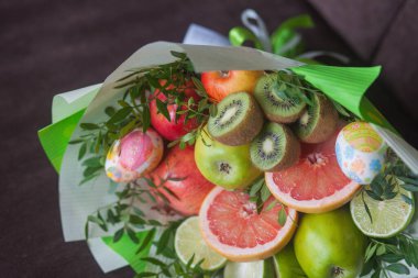 Çiçek buketi ve kalın kağıda sarılmış taze narenciye meyveleri.