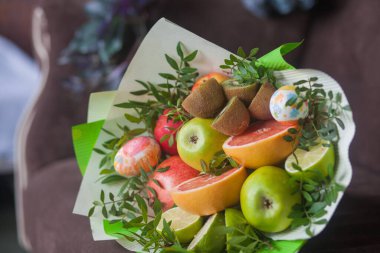Çiçek buketi ve kalın kağıda sarılmış taze narenciye meyveleri.