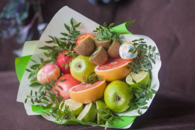 Çiçek buketi ve kalın kağıda sarılmış taze narenciye meyveleri.