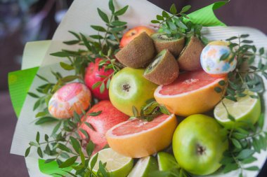 Çiçek buketi ve kalın kağıda sarılmış taze narenciye meyveleri.