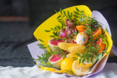 Çiçek buketi ve kalın kağıda sarılmış taze narenciye meyveleri.