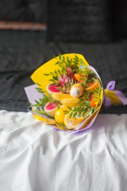 Çiçek buketi ve kalın kağıda sarılmış taze narenciye meyveleri.