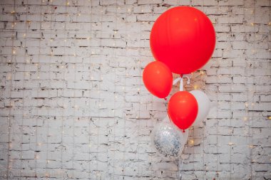 Tahta koltuk ve beyaz tuğla duvar arka planında büyük renkli balonlar. 
