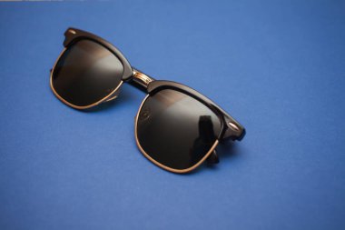 Mavi arkaplanda güneş gözlüğü, yakın plan.