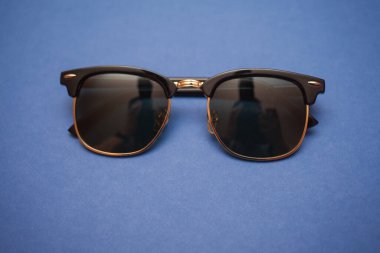 Mavi arkaplanda güneş gözlüğü, yakın plan.