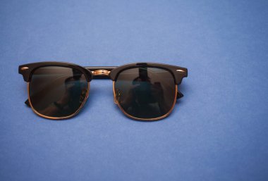 Mavi arkaplanda güneş gözlüğü, yakın plan.