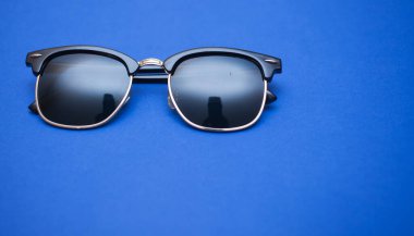 Mavi arkaplanda güneş gözlüğü, yakın plan.