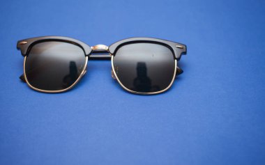 Mavi arkaplanda güneş gözlüğü, yakın plan.