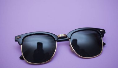 Mor arkaplanda güneş gözlüğü, yakın plan.