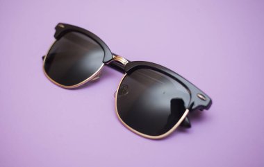 Mor arkaplanda güneş gözlüğü, yakın plan.