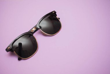 Mor arkaplanda güneş gözlüğü, yakın plan.