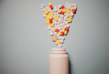 Çeşitli ilaç hapları, haplar, kapsüller ve mavi arka planda şişe.