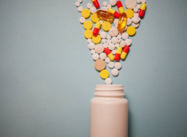 Çeşitli ilaç hapları, haplar, kapsüller ve mavi arka planda şişe.