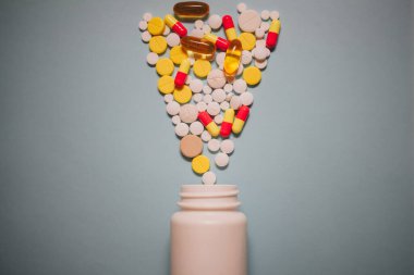 Çeşitli ilaç hapları, haplar, kapsüller ve mavi arka planda şişe.