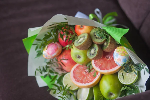 Çiçek buketi ve kalın kağıda sarılmış taze narenciye meyveleri.