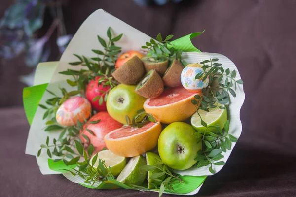 Çiçek buketi ve kalın kağıda sarılmış taze narenciye meyveleri.