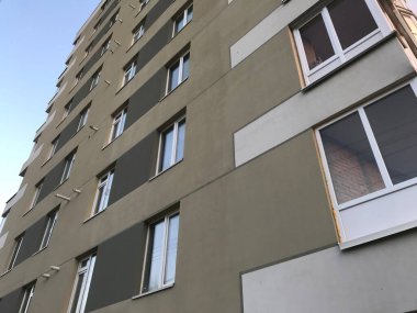 Güneşli bir günde mavi gökyüzü olan modern apartmanlar. Modern bir apartmanın cephesi