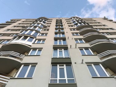 Güneşli bir günde mavi gökyüzü olan modern apartmanlar. Modern bir apartmanın cephesi