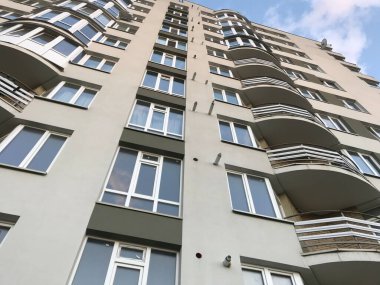 Güneşli bir günde mavi gökyüzü olan modern apartmanlar. Modern bir apartmanın cephesi