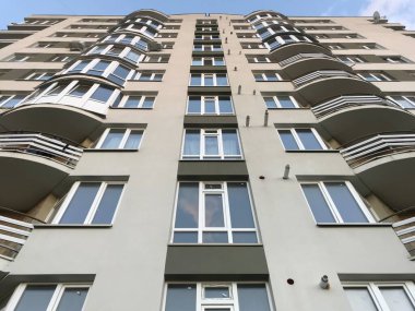 Güneşli bir günde mavi gökyüzü olan modern apartmanlar. Modern bir apartmanın cephesi