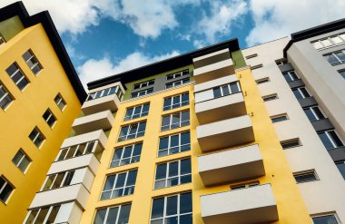 Güneşli bir günde mavi gökyüzü olan modern apartmanlar. Modern bir apartmanın cephesi