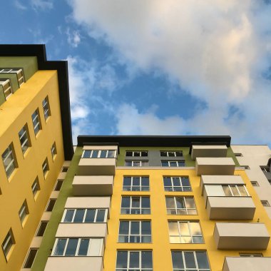 Güneşli bir günde mavi gökyüzü olan modern apartmanlar. Modern bir apartmanın cephesi