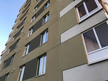 Güneşli bir günde mavi gökyüzü olan modern bir apartman. Modern bir apartmanın cephesi