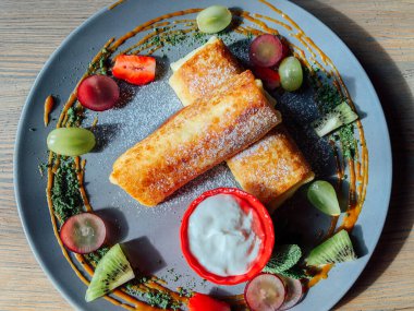 Tatlı soslu kızarmış krep ve egzotik meyveler. İnce krepli nefis kahvaltı.