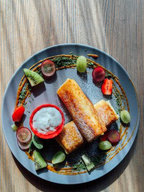 Tatlı soslu kızarmış krep ve egzotik meyveler. İnce krepli nefis kahvaltı.