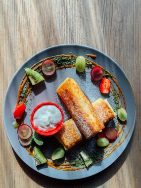 Tatlı soslu kızarmış krep ve egzotik meyveler. İnce krepli nefis kahvaltı.