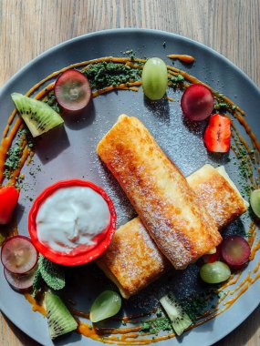 Tatlı soslu kızarmış krep ve egzotik meyveler. İnce krepli nefis kahvaltı.