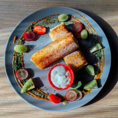 Tatlı soslu kızarmış krep ve egzotik meyveler. İnce krepli nefis kahvaltı.