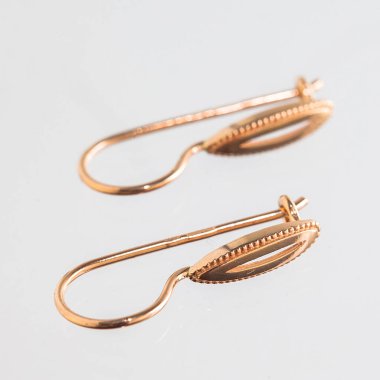 Beyaz arka planda izole edilmiş bir çift altın küpe.