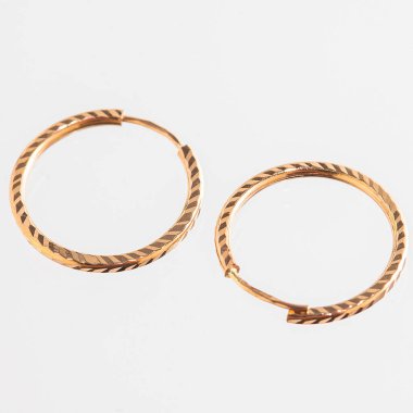 Beyaz arka planda izole edilmiş bir çift altın küpe.