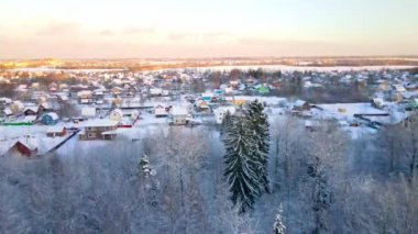Drone flight through snowy forest at sunset