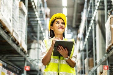 Dijital tablet kullanarak gülümseyen Asyalı kadınların portresi dağıtım deposu fabrikası, lojistik iş planlama konsepti raflarındaki stok ürün sayılarını kontrol etmek
