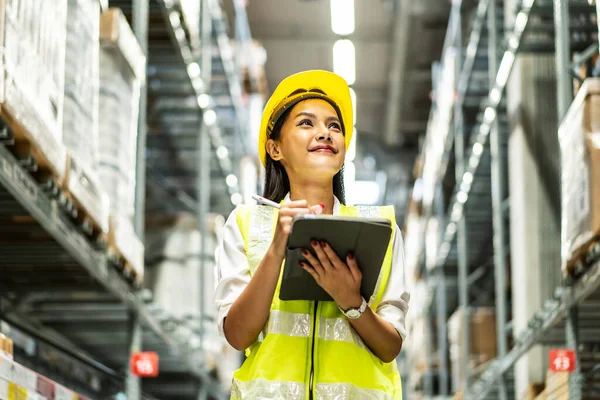 Dijital tablet kullanarak gülümseyen Asyalı kadınların portresi dağıtım deposu fabrikası, lojistik iş planlama konsepti raflarındaki stok ürün sayılarını kontrol etmek